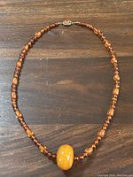 Full view of the amber bead necklace laid flat on a wooden surface.