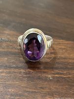 Close-up of ring face showing large oval faceted purple amethyst set in sterling silver bezel.