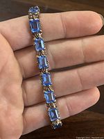 Hand-held close-up showing detail of rectangular blue stones set in sterling silver links.