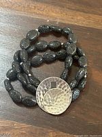 Close-up image of the lava rock beads showing their porous texture and the hammered sterling silver clasp.