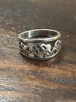 Close-up image of the sterling silver elephant ring showing detailed elephant figures on a wood surface.