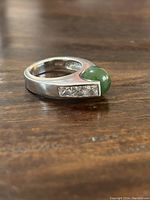 Side view of sterling silver ring showing green jade stone and clear rectangular accent stones