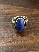 Top view of sterling silver ring with prominent oval lapis lazuli stone on a wooden surface.