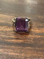 Front view of the sterling silver ring with rectangular-cut deep purple amethyst on wooden surface.
