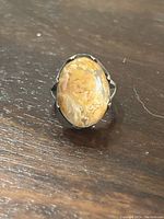 Close-up image of the sterling silver ring featuring an oval beige and white stone on a dark surface.