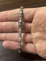 Close-up photo showing the design, clear stones, and clasp of the sterling silver tennis bracelet held in hand.