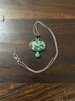 Full view of the necklace and pendant lying flat on a wooden surface.