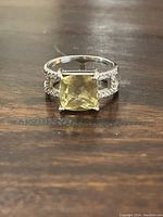 Front view of the sterling silver ring with yellow stone and accent stones on a wooden surface.