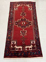 Full view of the vintage Persian rug showing the single medallion pattern and border design in rich red and blue colors.