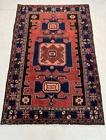 Full view of the rug laid flat showing red field, central medallion and border
