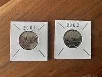 Front side of two 2002 Mens Hockey quarters with hockey goalie and net design in holders