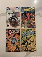 Four comic books laid out showing covers featuring Spider-Man, Daredevil, X-Factor, and Annual Kings of Pain.