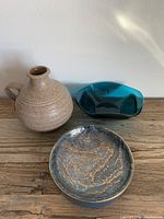 Group photo of three items: ceramic jug, teal glass dish, blue/gold ceramic ashtray