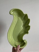 Front view of lime green paisley shaped ceramic dish held in hand to show size and shape.