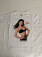 Full front view of the white t-shirt laid out flat showing Selena's full image and signature print.