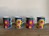 Four Royal Doulton bone china mugs in colorful South Pacific floral pattern shown side by side, front view of mug surfaces with large flowers in pink, yellow, purple, and orange.