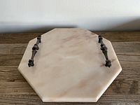 Octagonal stone vanity tray top view showing polished surface and decorative metal handles attached on two opposite sides.
