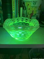 Vaseline glass bowl illuminated by UV light revealing characteristic yellow-green fluorescence.