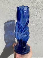 Side view of vintage blue glass hand vase showing detailed fingers and glossy finish.