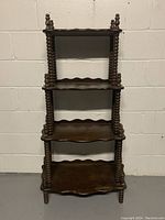 Full front view of vintage wood spindle display shelf showing all four shelves and spindle columns on each corner.