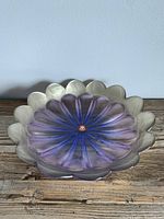 Front view of the glass plate showing lilac and blue radiating pattern with gold scalloped edges on wooden surface.