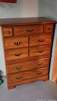 Front view of the wooden dresser showing five drawers and metal hardware.