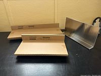 Three shelves visible: one out of box, two stacked inside original cardboard boxes labeled LIMMAHN on black surface against yellow wall.