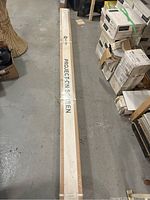 Long sealed cardboard case wrapped in plastic and strapped, printed "Projection Screen" along its length