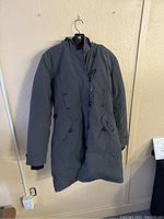 Full front view of grey parka hanging on wall