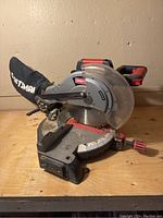 Front-left angled view of the Craftsman miter saw showing the dust collection bag and handle.