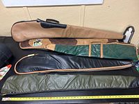 Five long firearm cases in various sizes and designs laid out on a table.