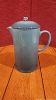 Full view of the blue Le Creuset French press showing its shape and handle.