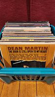 Photo showing a collection of vinyl records stacked upright with Dean Martin's album cover "The Door Is Still Open To My Heart" facing forward.