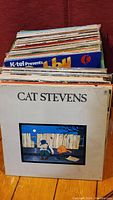 Stack of assorted vinyl records showing Cat Stevens album in front with illustrated cover