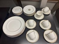 Full overview of the dinnerware set arranged on a table showing large and medium plates, side plates, cups, and saucers.