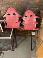 Overview of two red barn-shaped Purple Martin birdhouses mounted on black metal stakes, showing front sides with perches and entry holes.