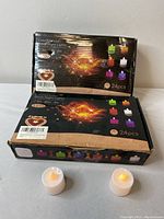 Two unopened boxes of Flower brand Colorful Color LED tea lights, each box labeled 24 pieces. Two individual LED tea lights displayed in front of the boxes.