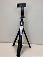 Full view of folded ANXRE 60-inch selfie stick tripod showing adjustable phone mount and tripod legs.