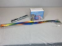 Overview of the set showing electronic interactive cat toy box and rainbow-colored reflective collar in package on gray surface.