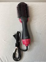 Full view of the hair straightening brush showing the bristle section, handle, and power cord.