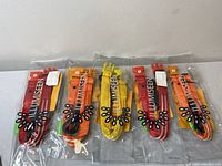 Five Illumiseen branded dog collars in red, orange, and yellow, sealed in clear plastic packaging, arranged side by side on a white surface.