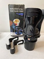 Photo of the multifunctional car cup holder expander adapter displayed next to its original packaging box showing front and side compartments.