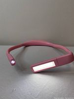 Pink flexible neck lamp on a flat surface showing white LED light at one end and warm LED panel on the other