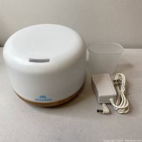 Front and top view of the Miserve humidifier with adapter and cup on a grey surface.