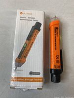 Photo of Eoteck NTK009 non-contact voltage test pen alongside its original box, showing the front design and branding.
