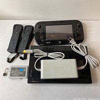Full set including Wii U console base, GamePad controller, two Wii remotes, rechargeable battery pack, power charger, and HDMI cable, laid out for visual inspection.