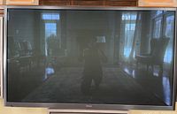 60" Samsung TV mounted on wall showing reflection of room