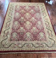 Full view of burgundy and cream floral area rug laid on wood floor