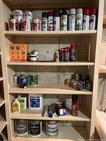 Four shelves of assorted paint and spray paint cans, caulking tubes and bottles, varathane products, rust paints, and primers. Items fully shelved with visible label details.