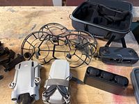 Overview showing two DJI Mini 3 Pro drones, propeller guards, DJI RC-N1 controller, charging hub, carrying case and other accessories